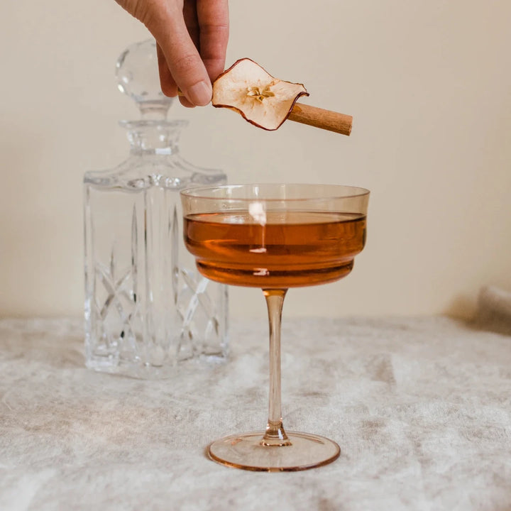 A glass jar filled with dried apple slices, cinnamon sticks, and star anise. The jar has a white label with the Maiden Voyage logo and the product name 