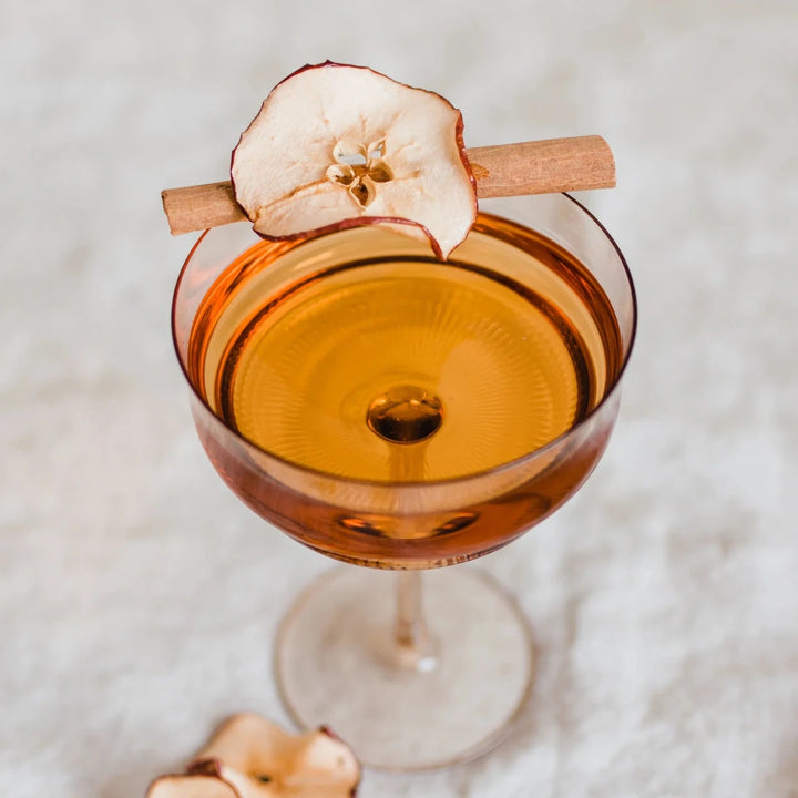 A glass jar filled with dried apple slices, cinnamon sticks, and star anise. The jar has a white label with the Maiden Voyage logo and the product name 