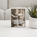 Greeting card with vintage photo and humorous quote on a surface with a plant in the background