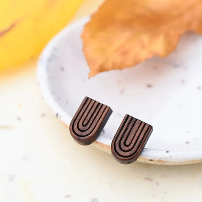 A pair of wooden earrings shaped like rainbows.
