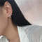 A pair of asymmetric twist earrings made of sterling silver, featuring a unique, abstract, and mismatched swirling design, displayed on a white plate. These modern earrings are available in Ottawa, Ontario, Canada
