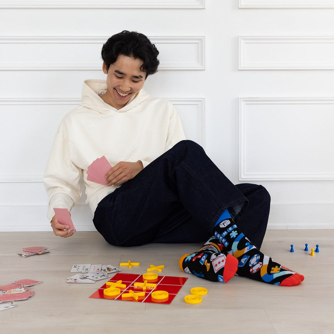 Person sitting on the floor playing a board game with colorful pieces and cards.