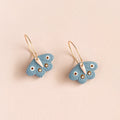 Butterfly-shaped earrings on a beige background