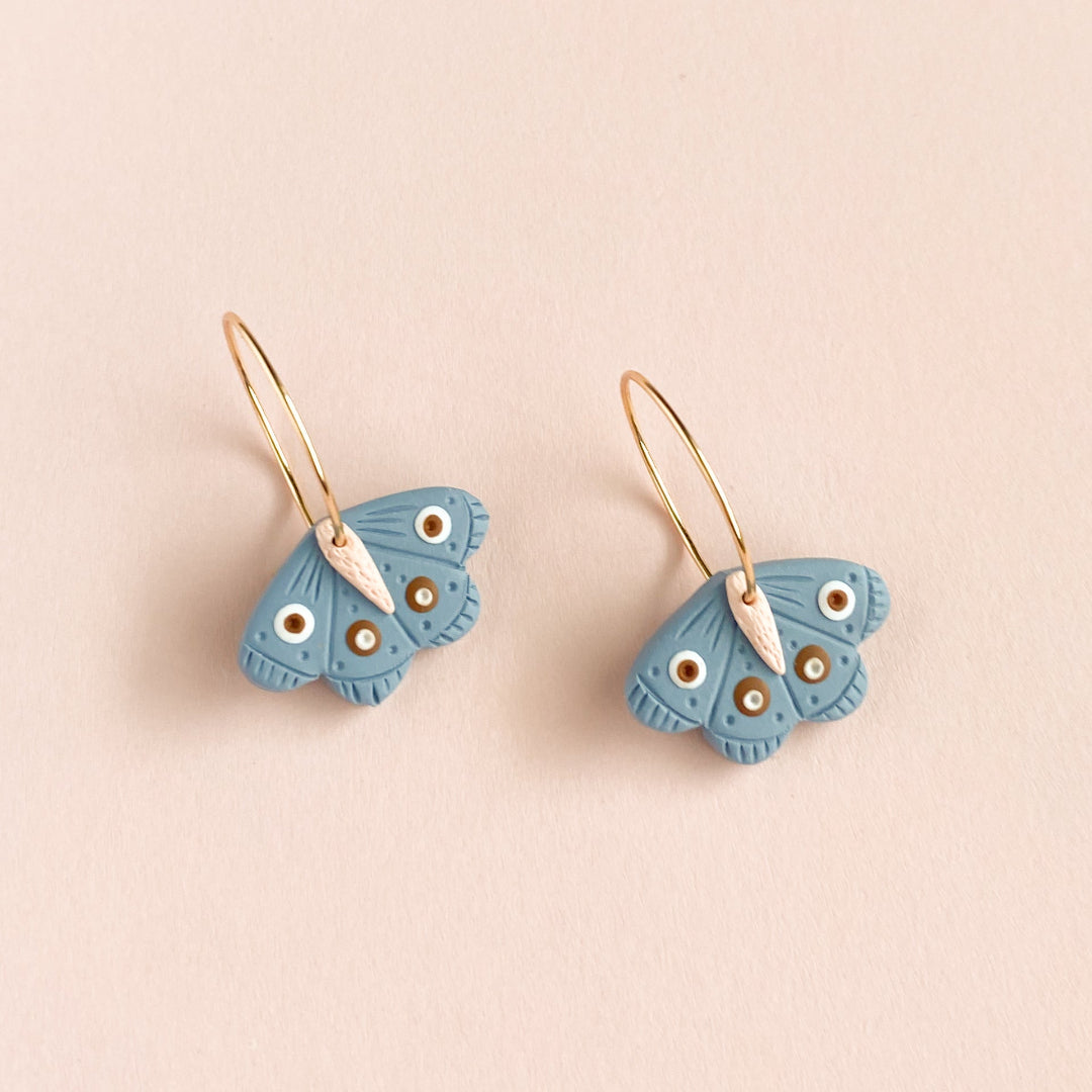 Butterfly-shaped earrings on a beige background