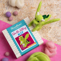 Needle felting kit with a green felted creature on a pink mat