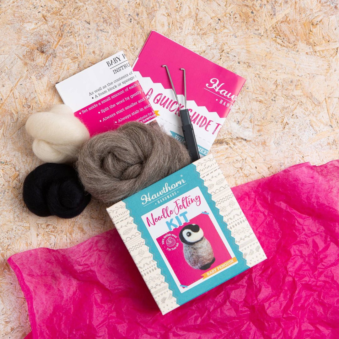 Knitting supplies including yarn, needles, and books on a textured surface