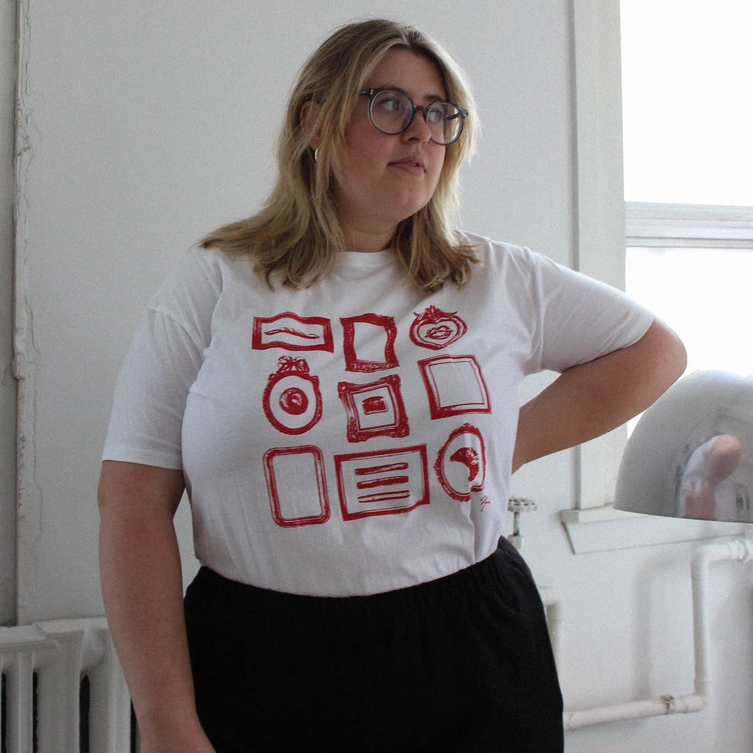Person wearing a white t-shirt with red graphics in a room with a window and radiator.