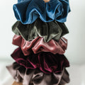 Stack of colorful velvet scrunchies on a white background