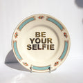 Decorative plate with 'Be Your Selfie' text on a white background