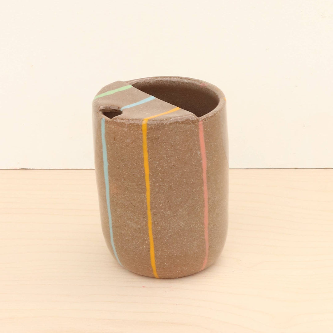 Ceramic cup with multicolored lines on a beige background