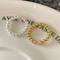 A set of silver and gold bead rings, each with a delicate design of small spheres and an adjustable, open band, displayed on a patterned ceramic surface. These dainty and stackable rings are available in Ottawa, Ontario, Canada.