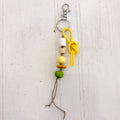 Keychain with colorful beads and a yellow knot on a light wooden background