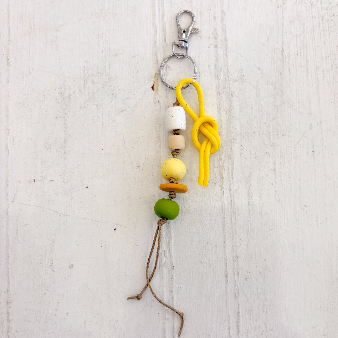 Keychain with colorful beads and a yellow knot on a light wooden background
