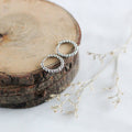 Silver hoop earrings on a wooden surface with dried flowers.
