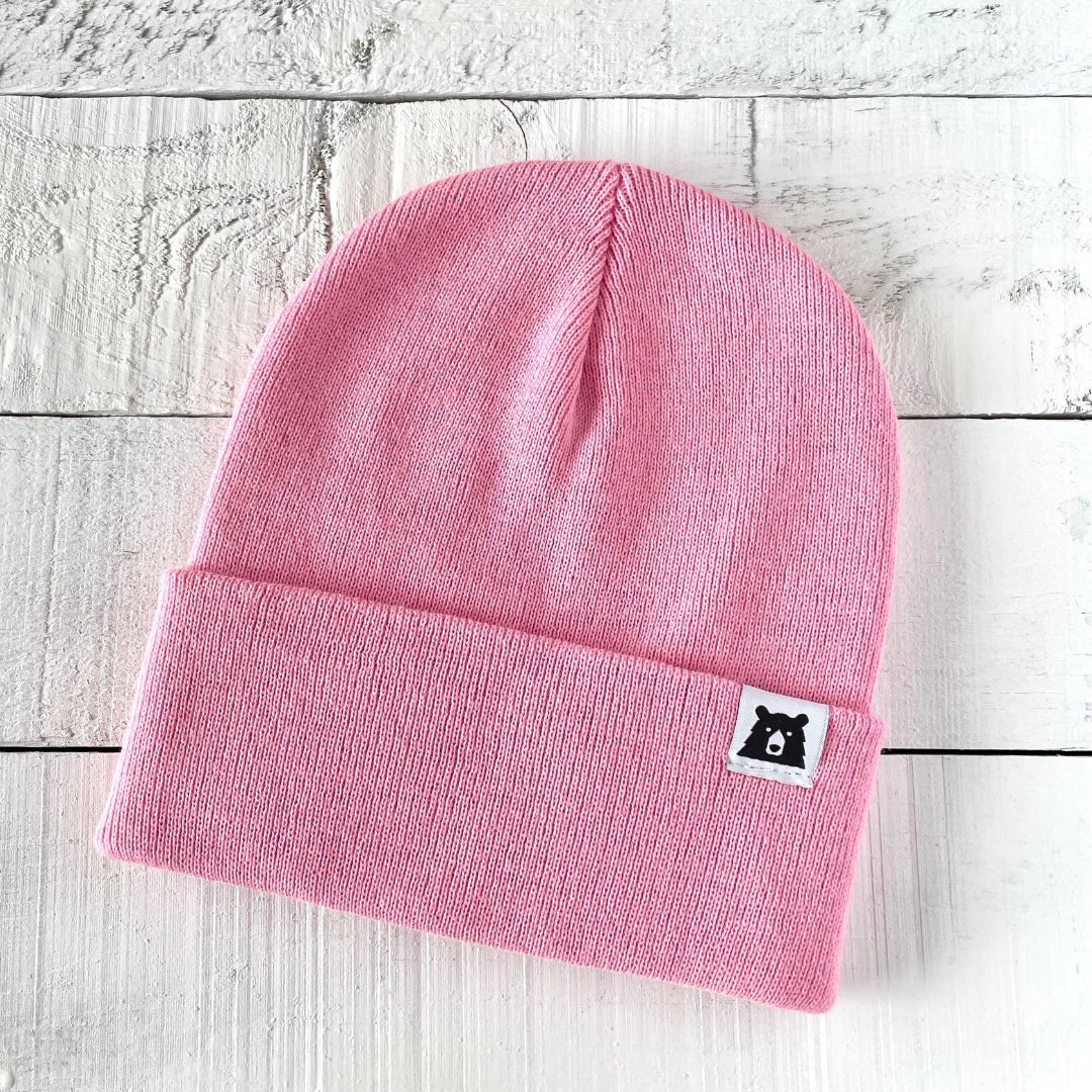 Pink beanie with a small label on a light wooden surface