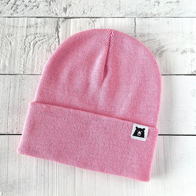 Pink beanie with a small label on a light wooden surface