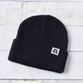 Black beanie with a logo on a light wooden surface