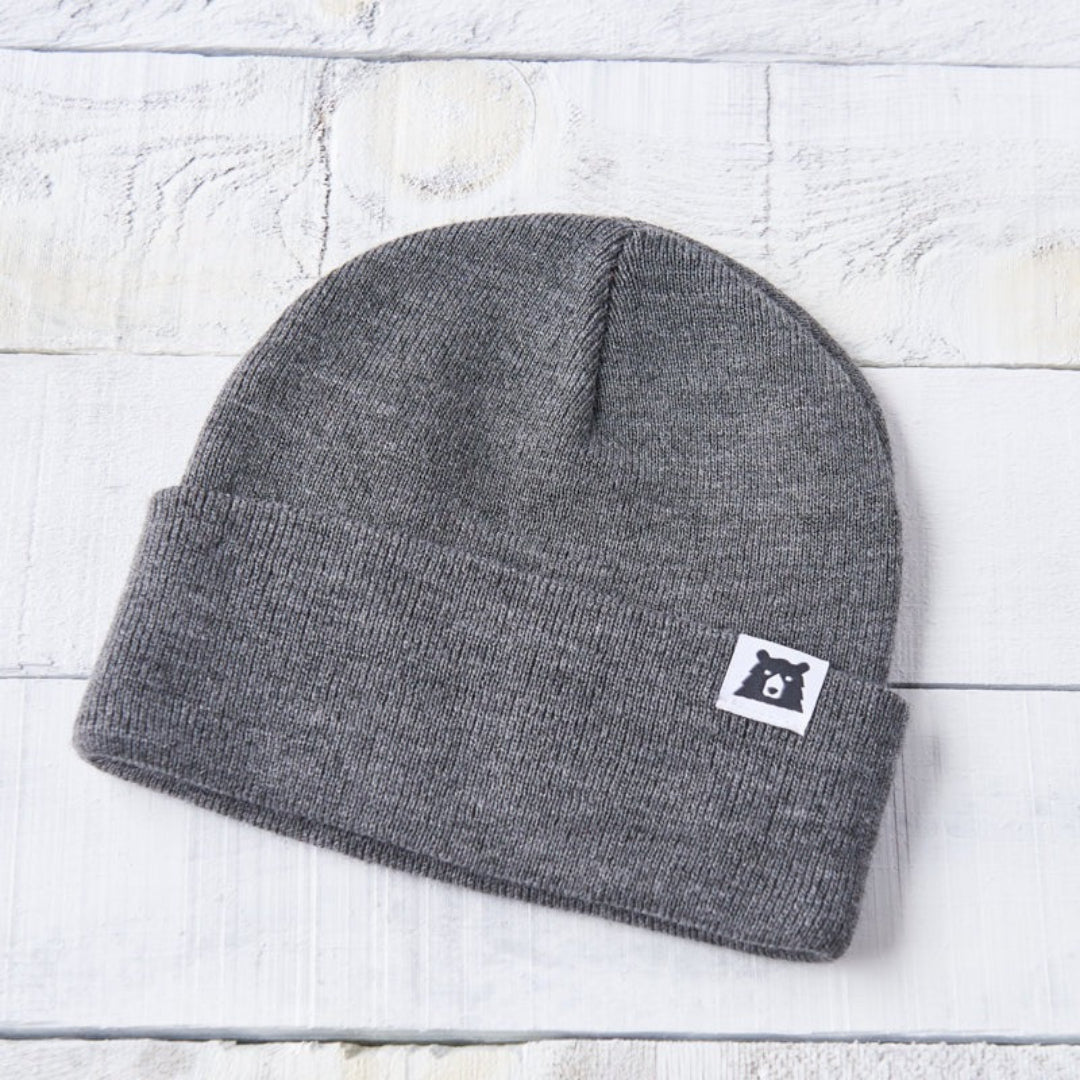 Gray beanie with a logo on a light wooden surface
