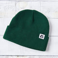 Green beanie with a logo on a white wooden surface