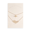 A pair of gold necklaces on a white card. The longer necklace features a honeycomb pendant, and the shorter necklace features a bee pendant. The card has the text "BIRCH JEWELLERY" and "EST-2011" printed on it.