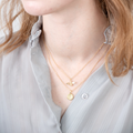 A pair of gold necklaces on a white card. The longer necklace features a honeycomb pendant, and the shorter necklace features a bee pendant. 