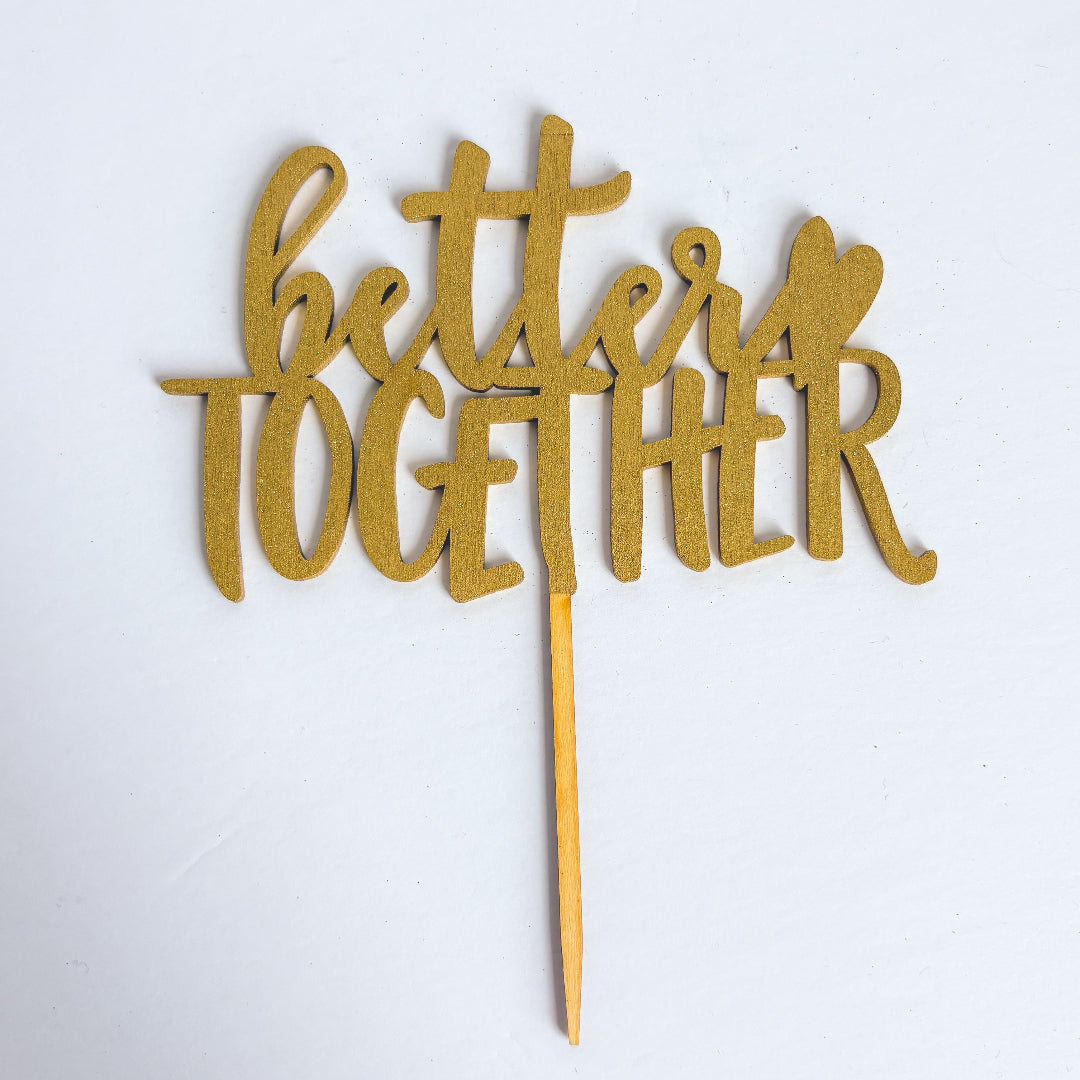 Gold 'better together' cake topper on a white background