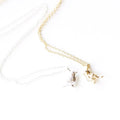 Two necklaces with bird pendants on a white marble surface. One necklace has a gold bird pendant, and the other has a silver bird pendant.