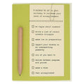 A green and cream-colored card featuring a checklist titled "8 THINGS 'TO DO' on your birthday to increase your level of accomplishment." A small wooden pencil is attached vertically to the left side of the card. The checklist items are "be vague about numbers," "write a list of recent notable triumphs," "make ice in preparation," "impart your wisdom on an unsuspecting passerby," "cry if you want to," "decide between pompoms and ponies," "make a wish," and "feel accomplished."