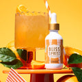 Bottle of Bliss Spritz with a cocktail and orange slices on a yellow background