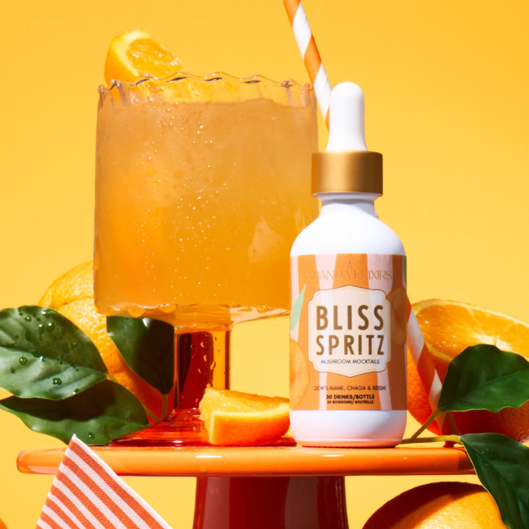 Bottle of Bliss Spritz with a cocktail and orange slices on a yellow background