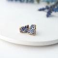 Pair of blue and gold earrings on a white plate with a blurred background