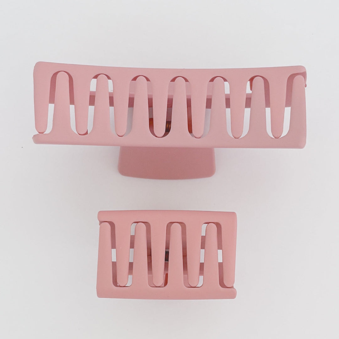 Two pink hair clips with a wavy design on a light gray background