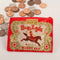 A small red coin purse with a zipper, featuring a vintage-style illustration of a woman riding a horse with a triumphant pose. The text 