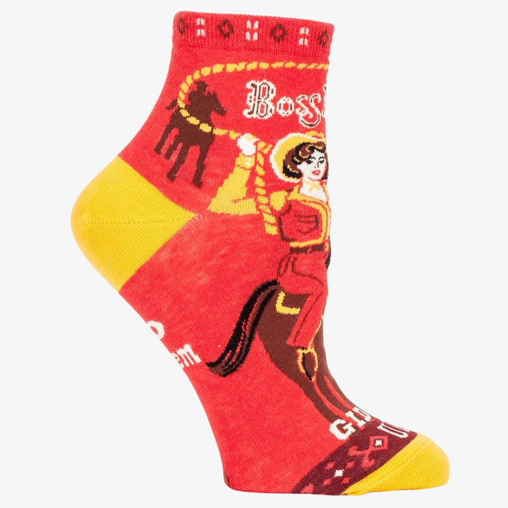 A pair of red ankle socks with yellow accents. One sock features a vintage-style illustration of a cowgirl riding a horse, with 
