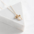 Gold bow-shaped necklace on a white surface