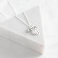Silver bow-shaped necklace on a white fabric background