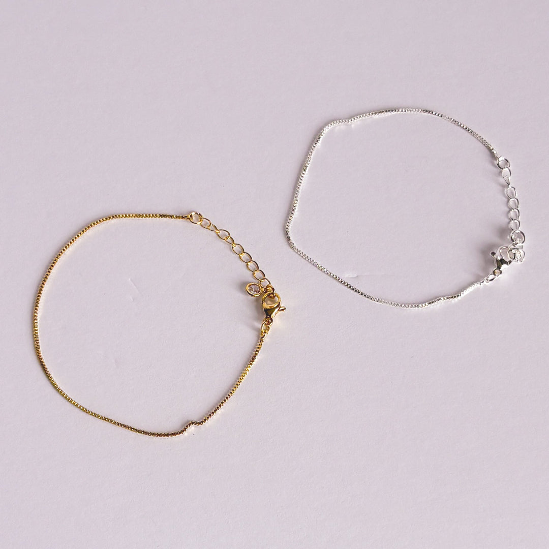 Gold and silver bracelets on a light gray background
