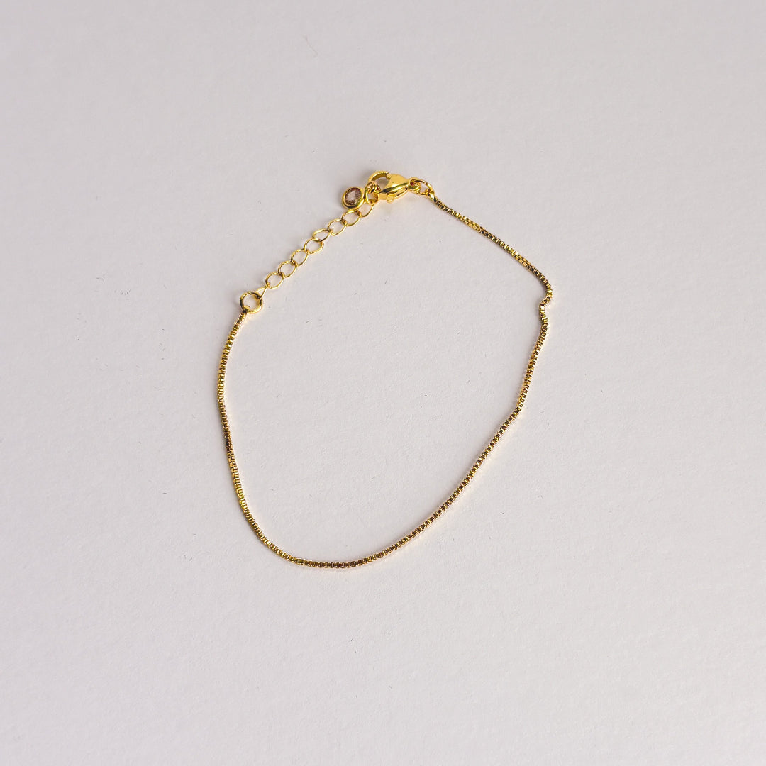 Gold bracelet on a light gray background