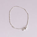 Silver bracelet with a small round charm on a light gray background