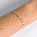 Silver bracelet on a person's wrist with a neutral background