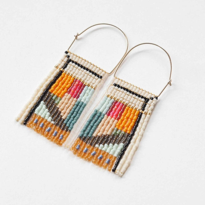 A pair of rectangular, tapestry-style earrings hand-stitched with small Japanese glass beads in a geometric pattern featuring shades of cream, orange, pink, light blue, teal, brown, and black. They hang from delicate, half-circle 14 KT gold filled wire hoops.