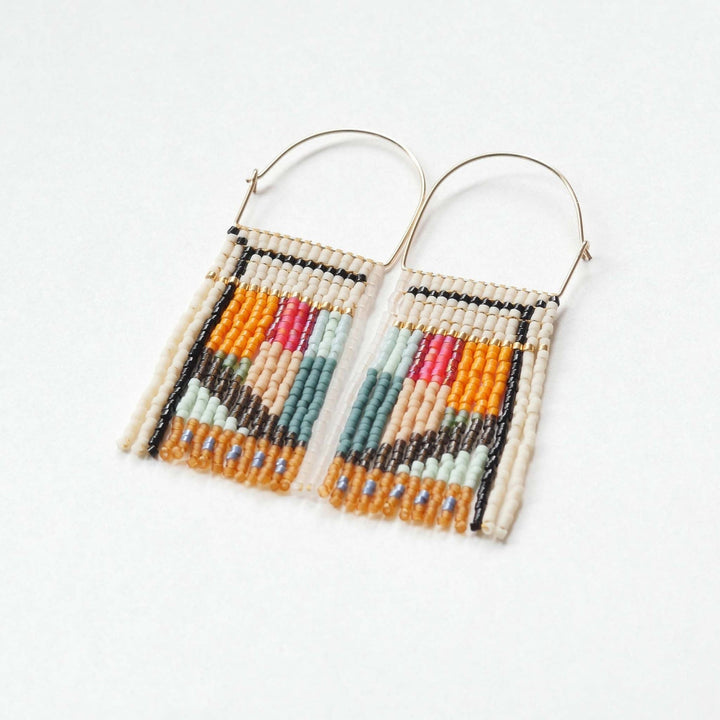 A pair of rectangular, tapestry-style earrings hand-stitched with small Japanese glass beads in a geometric pattern featuring shades of cream, orange, pink, light blue, teal, brown, and black. They hang from delicate, half-circle 14 KT gold filled wire hoops.