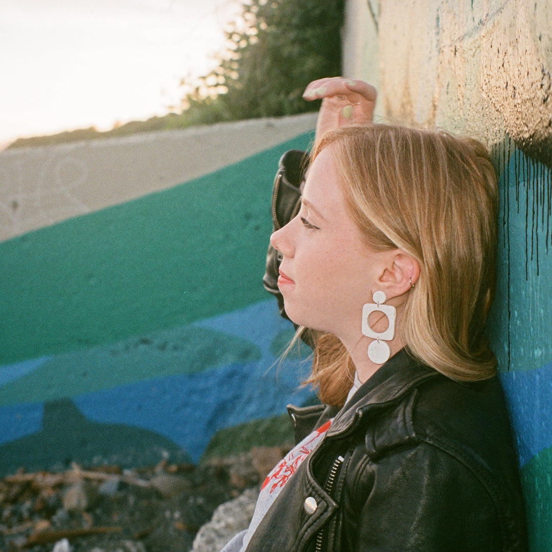 Person leaning against a colorful wall by the beach