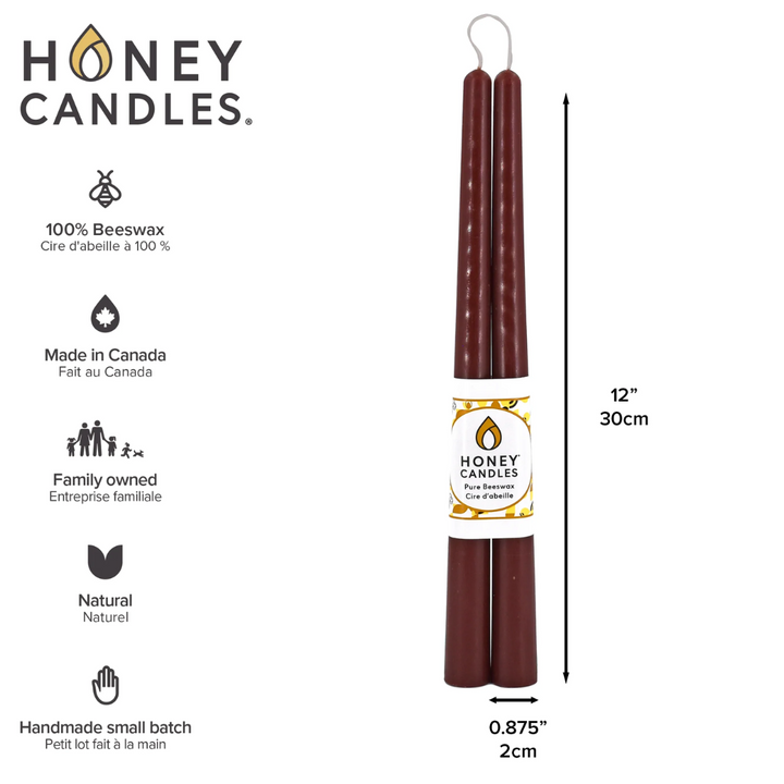 Two brown beeswax candles are standing upright, tied together with a string. The candles have a label that says 