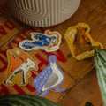 Stickers on a wooden surface with a plant pot in the background