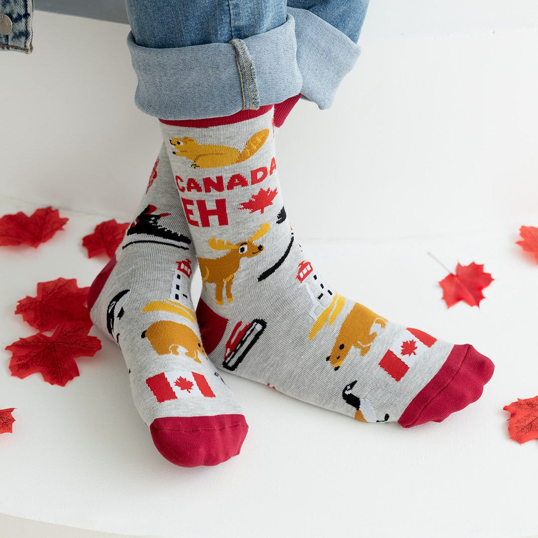 Person wearing socks with Canadian-themed design on a white surface with red maple leaf decorations.