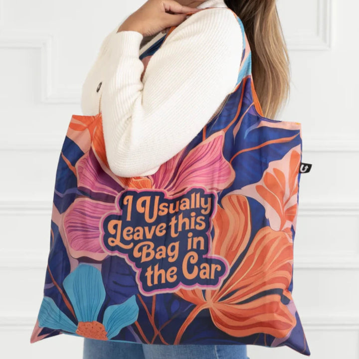 A colorful tote bag with a floral pattern and the text 
