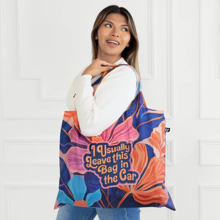 A colorful tote bag with a floral pattern and the text 