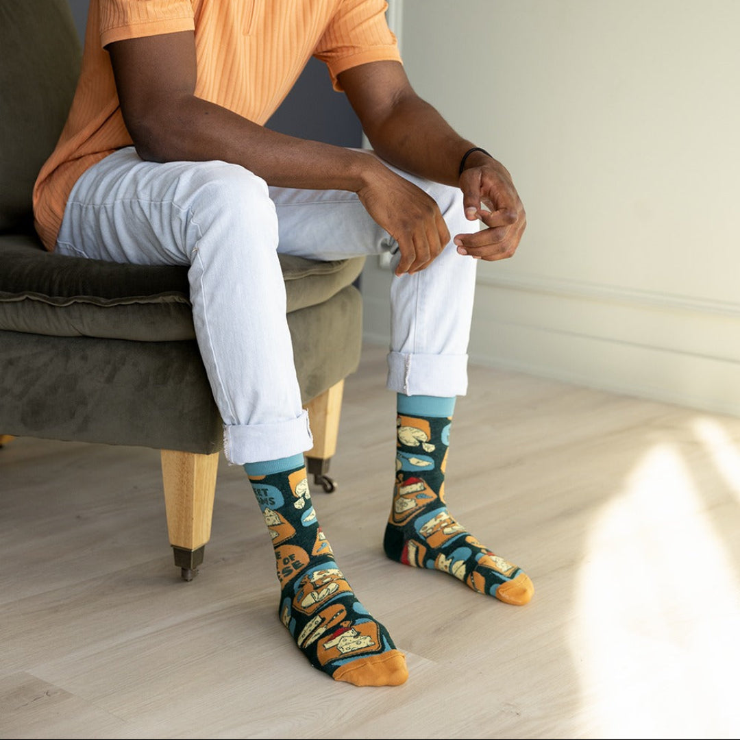 Man sitting on a chair wearing colorful socks with a neutral background