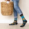A pair of black socks with a laundry-themed design. The socks feature a washing machine, detergent bottles, a laundry basket, and socks themselves. It reads "LAST CLEAN PAIR".